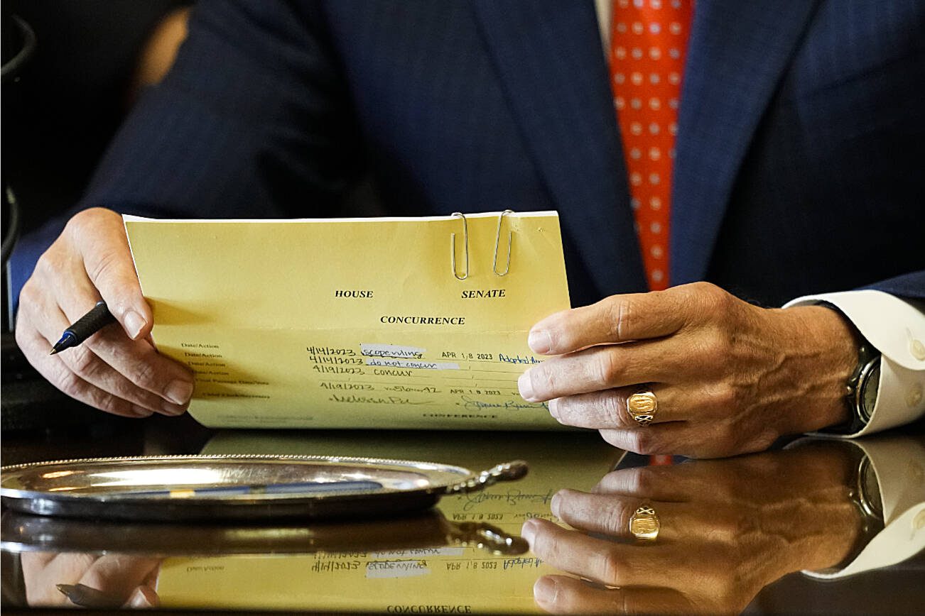 Washington Gov. Jay Inslee pauses as he holds House Bill 1240, which prohibits the manufacture, importation, distribution and sale of semi-automatic assault-style weapons in the state, before signing it into law, Tuesday, April 25, 2023, at the Capitol in Olympia, Wash. (AP Photo/Lindsey Wasson)