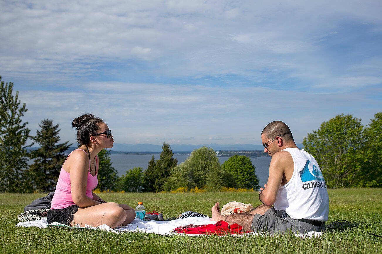 Tawny Mandracken blows a teasing kiss at her husband Garrick after he lost a round of cards as they duo enjoys the sunny weather at Harborview Park on Tuesday, May 9, 2017 in Everett, Wa. (Andy Bronson / The Herald)