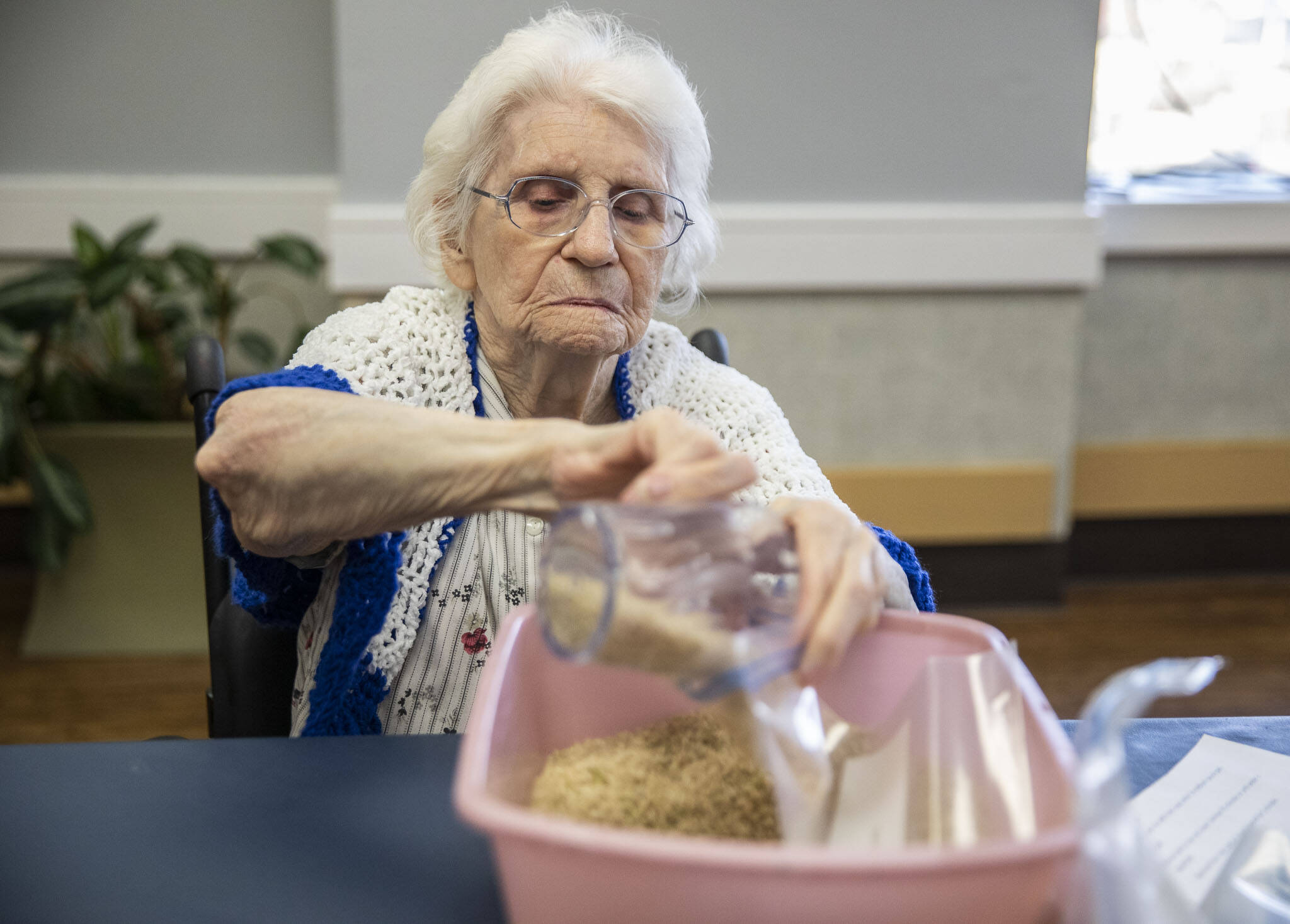Ellen Douglas fills a bag with brown rice for Faith Food Bank donations on Tuesday, May 2, 2023 in Everett, Washington. (Olivia Vanni / The Herald)