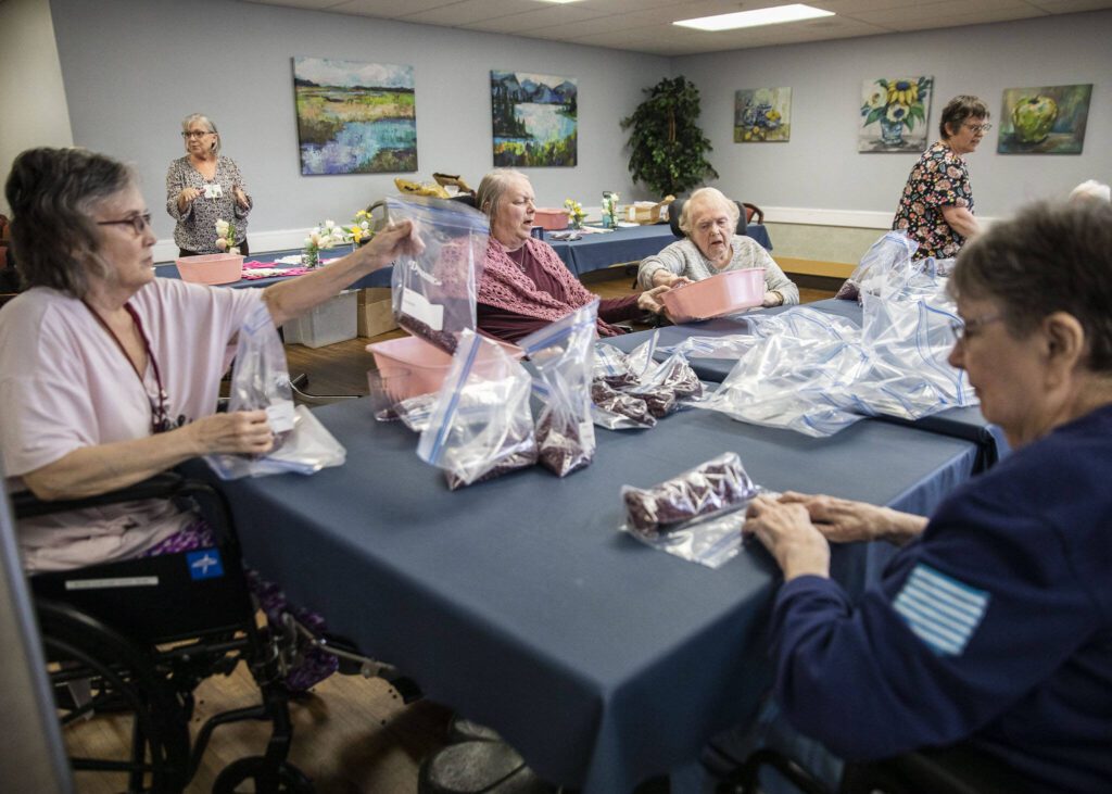 Ellen Douglas fills a bag with beans for Faith Food Bank donations on Tuesday, May 2, 2023 in Everett, Washington. (Olivia Vanni / The Herald)
