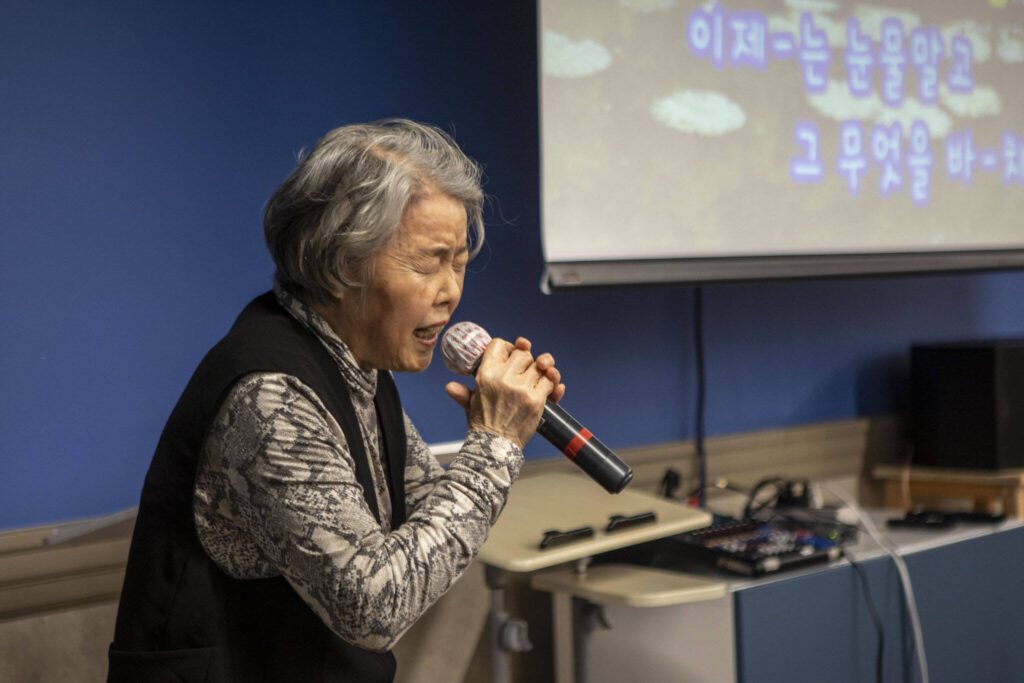 Sung Lee sings during a senior community meals program focused on the Korean community at Homage in Lynnwood, Washington on Thursday, May 4, 2023. (Annie Barker / The Herald)
