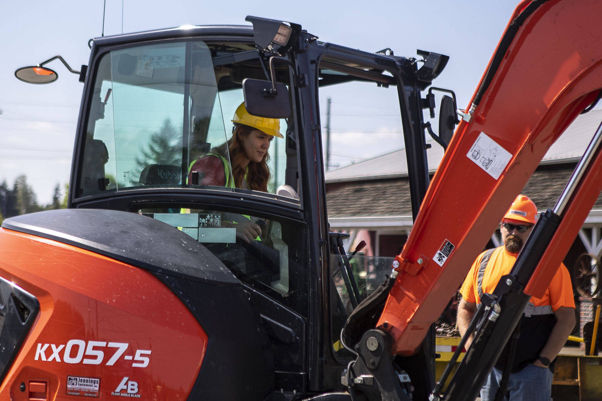 Jessica Eames, left, tries out equipment instructed by Justin Martin, right, during a trade fair at the Evergreen State Fairgrounds in Monroe, Washington on Wednesday, May 3, 2023. High school kids learned about various trades at the event. (Annie Barker / The Herald)