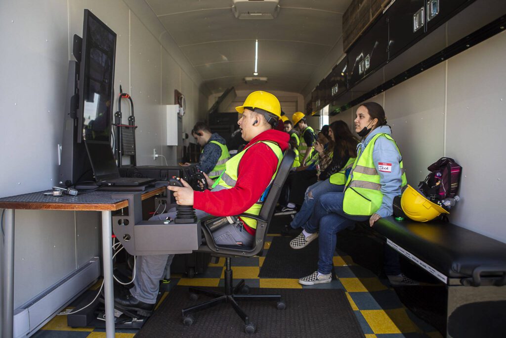 Toby Guggenmos tries out an equipment simulation during a trade fair at the Evergreen State Fairgrounds in Monroe, Washington on Wednesday, May 3, 2023. High school kids learned about various trades at the event. (Annie Barker / The Herald)
