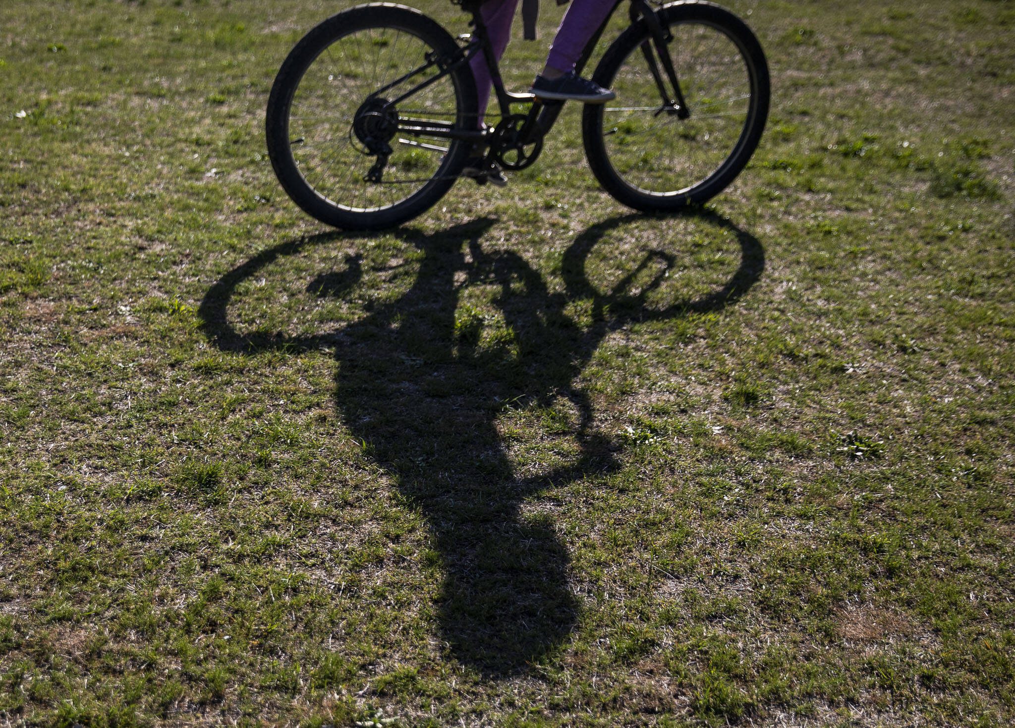 A students shadow is cast on the ground as they ride their bike during a bike safety class at Darrington Elementary School on Friday, May 12, 2023 in Darrington, Washington. (Olivia Vanni / The Herald)