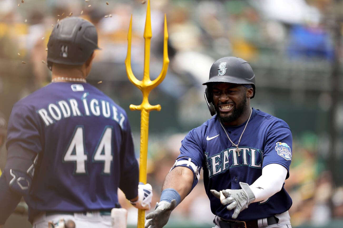 Seattle Mariners' Taylor Trammell, right, celebrates with teammate Julio Rodriguez (44) in the dugout after hitting a two-run home run against the Oakland Athletics during the third inning of a baseball game in Oakland, Calif., Thursday, May 4, 2023. (AP Photo/Tony Avelar)