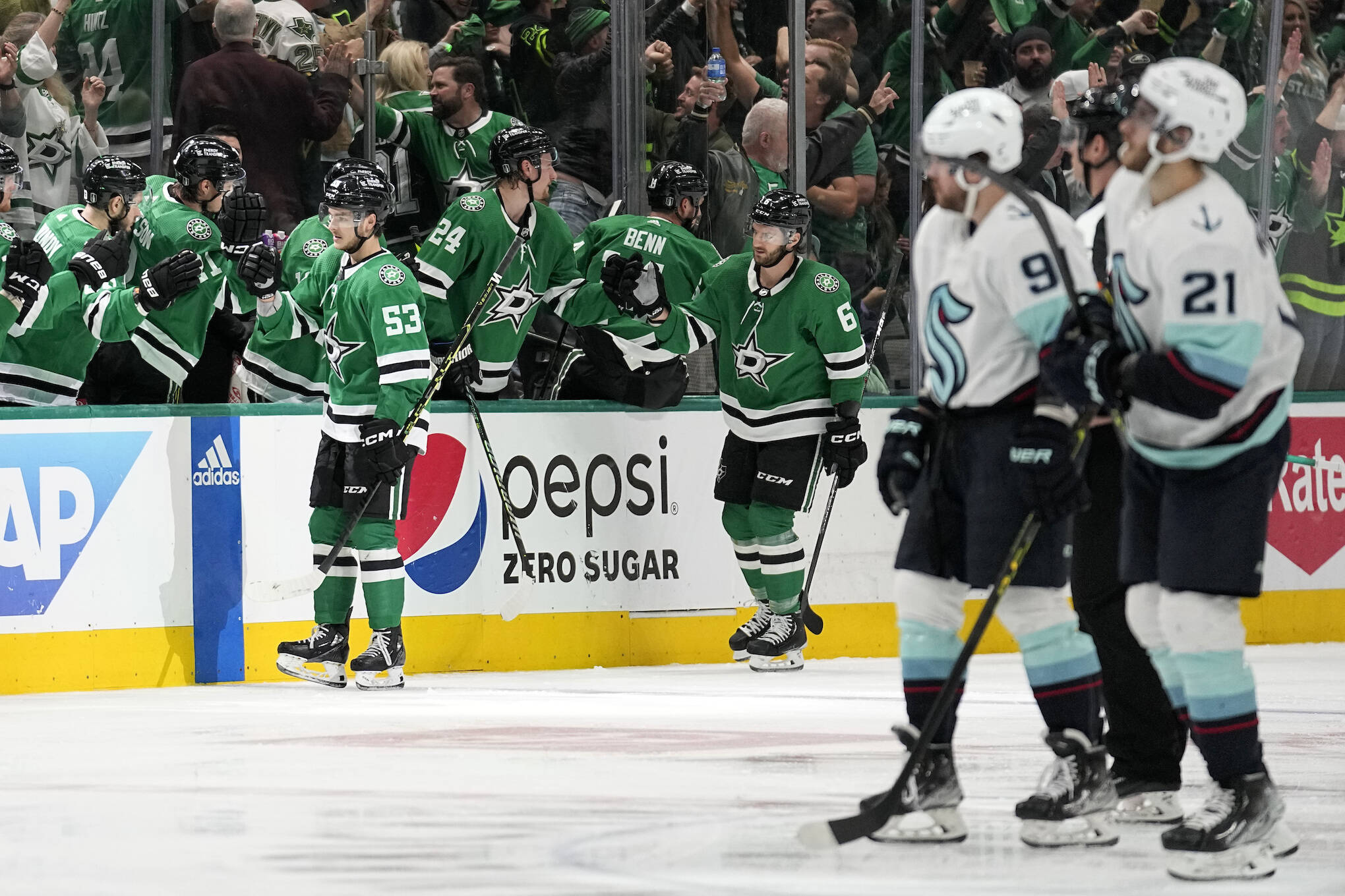 The Stars’ Wyatt Johnston (53) and Colin Miller (6) celebrate with the bench after Johnston scored as the Kraken’s Ryan Donato (9) and Alex Wennberg (21) skate past in the second period of Game 2 of second-round playoff series Thursday in Dallas. (AP Photo/Tony Gutierrez)