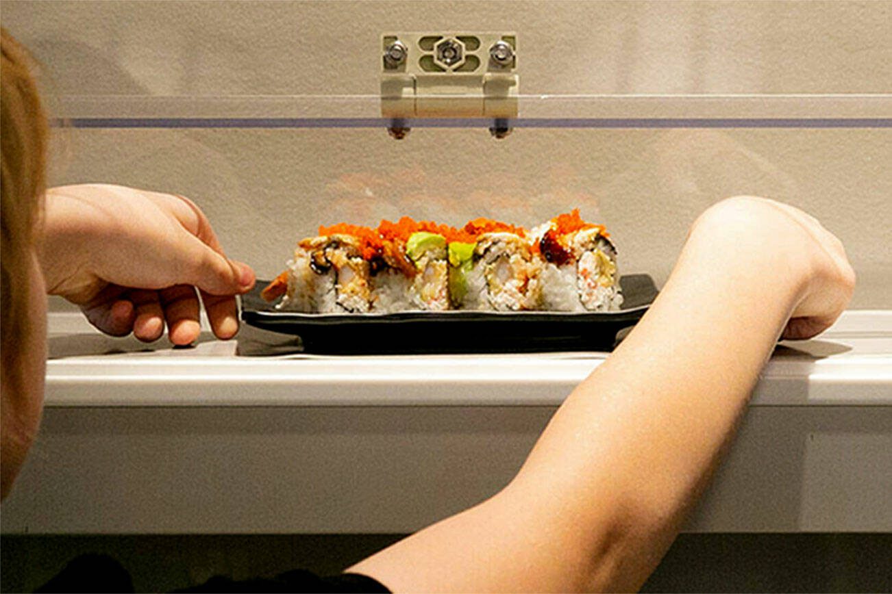 Levi Arneson, 12, grabs a roll from the monorail system next to his table at Sushi Hana on Jan. 5, in Lynnwood. (Ryan Berry / The Herald)