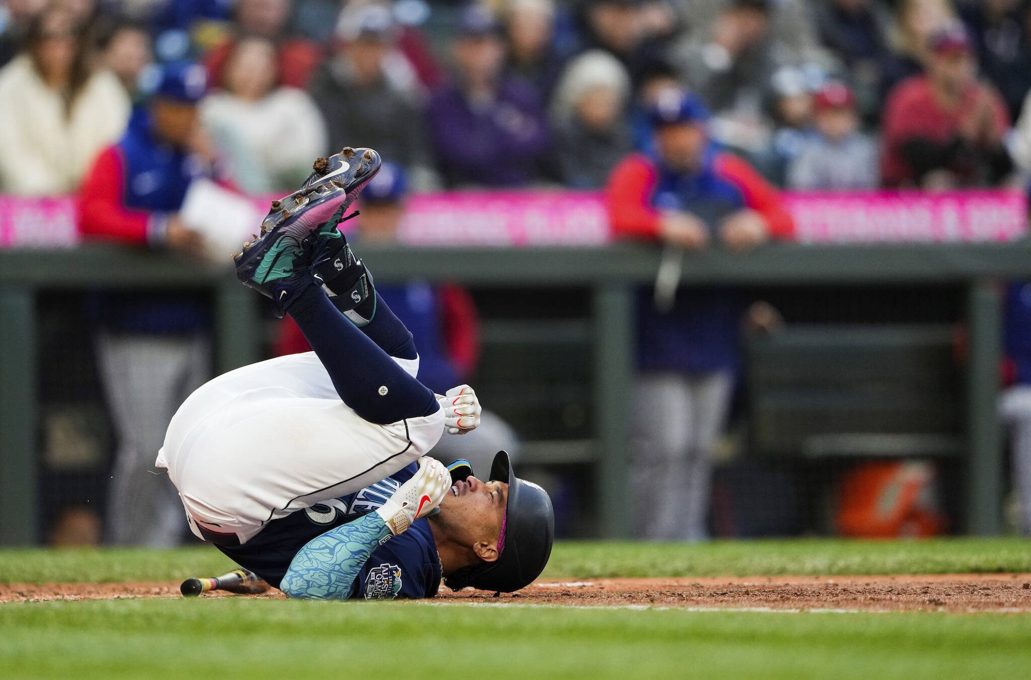 The Mariners’ Kolten Wong falls on the ground after being hit by a pitch by Rangers starting pitcher Jon Gray during the fifth inning of a game Monday in Seattle. (AP Photo/Lindsey Wasson)