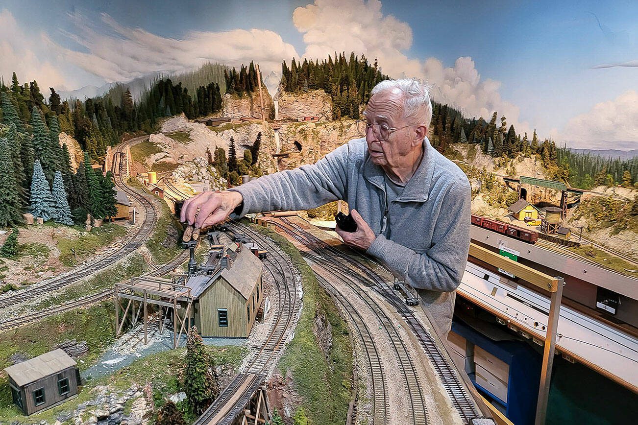 Tom Treanor, member of the Swamp Creek & Western Railroad Association, operating on a portion of the model railroad set in the Cascade mountains. (Photo by John Dineen)