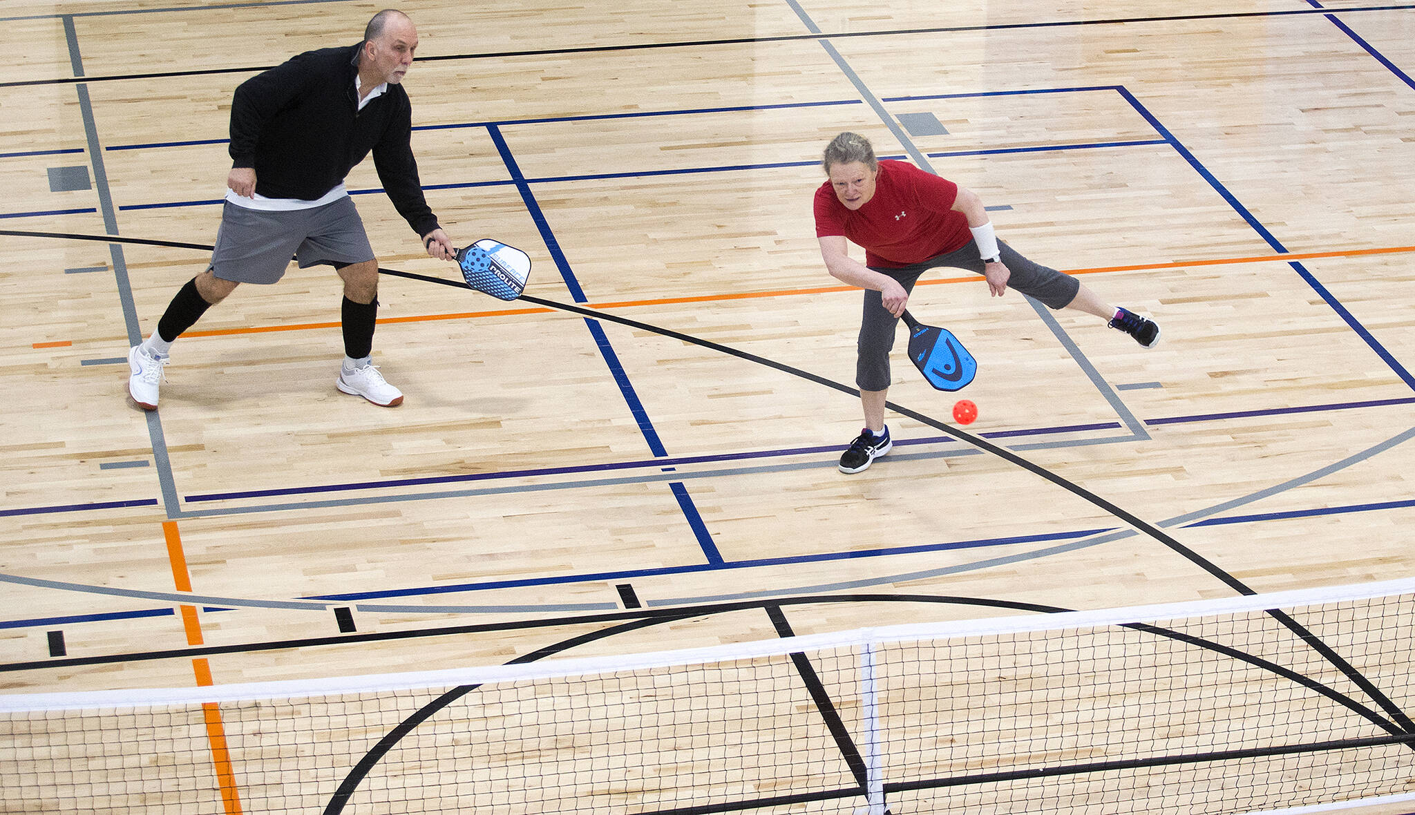Kathy Kamel returns a volley as teammate George Jones backs her up during a pickleball game at the Everett YMCA on in February, 2020 in Everett. (Andy Bronson / The Herald file photo)