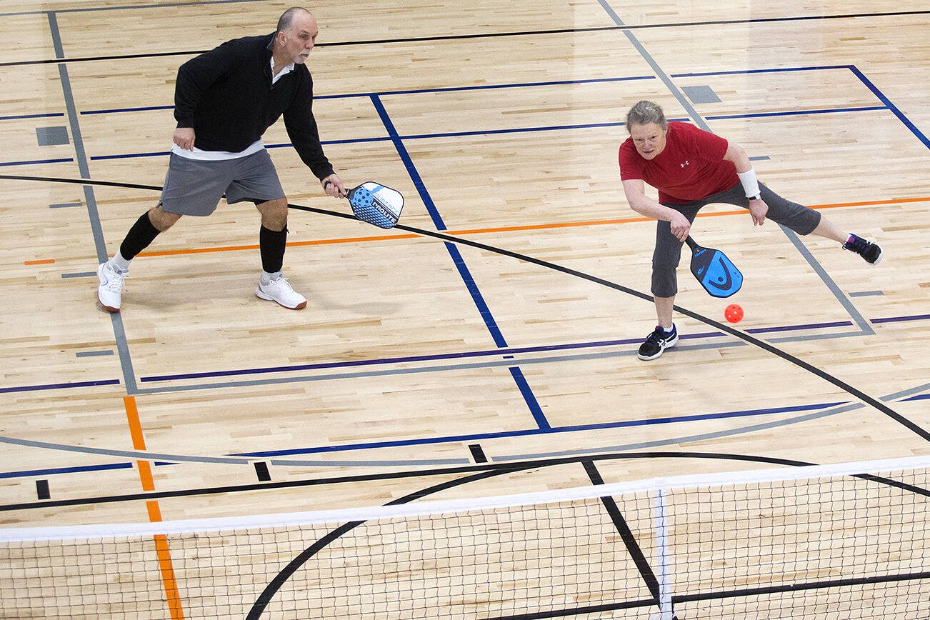 Kathy Kamel returns a volley as teammate George Jones backs her up during a pickleball game at the Everett YMCA on Wednesday, Feb. 26, 2020 in Everett, Wash. (Andy Bronson / The Herald)