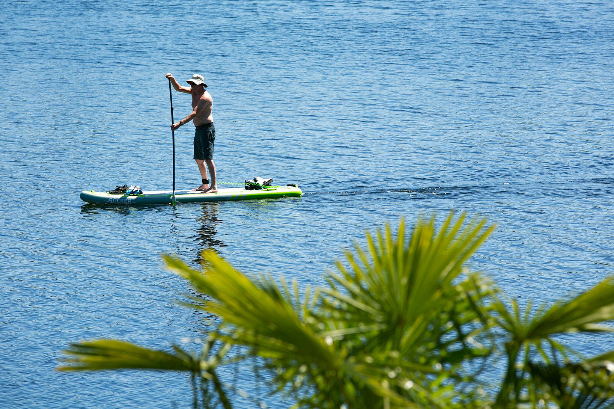 A man paddle boards along Silver Lake during a hot and sunny afternoon on Friday, May 12, 2023, in Everett, Washington. (Ryan Berry / The Herald)