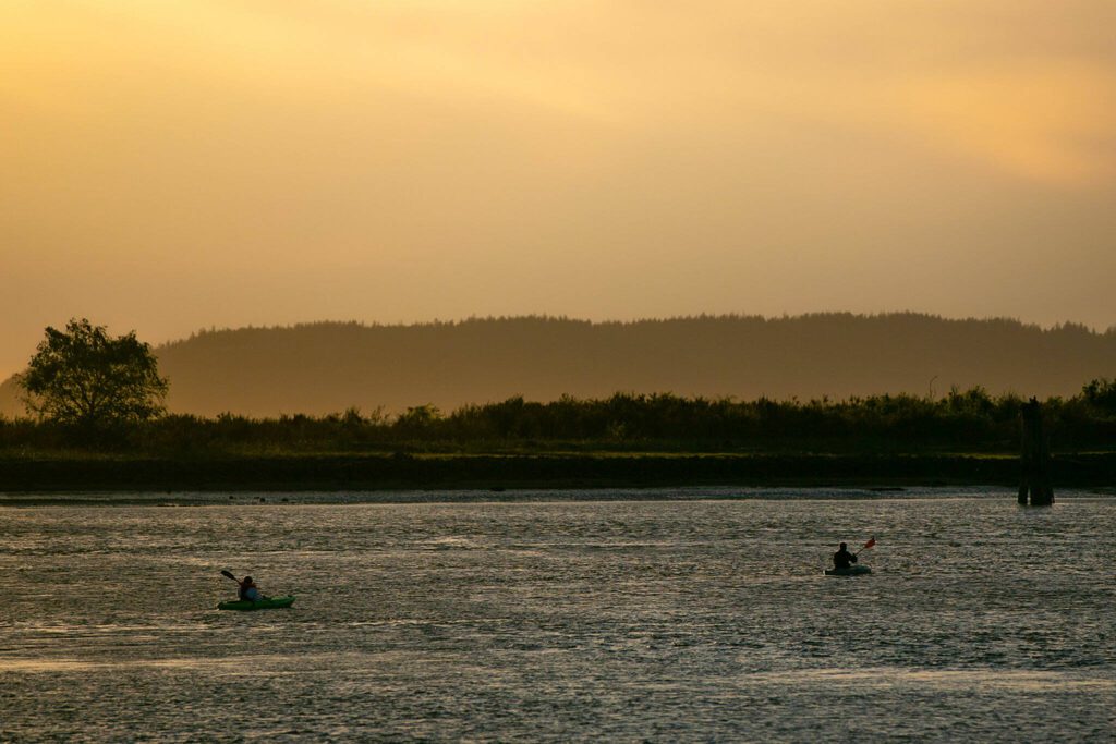 Two kayakers head out to Jetty Island as the sun sets on Thursday. (Ryan Berry / The Herald)
