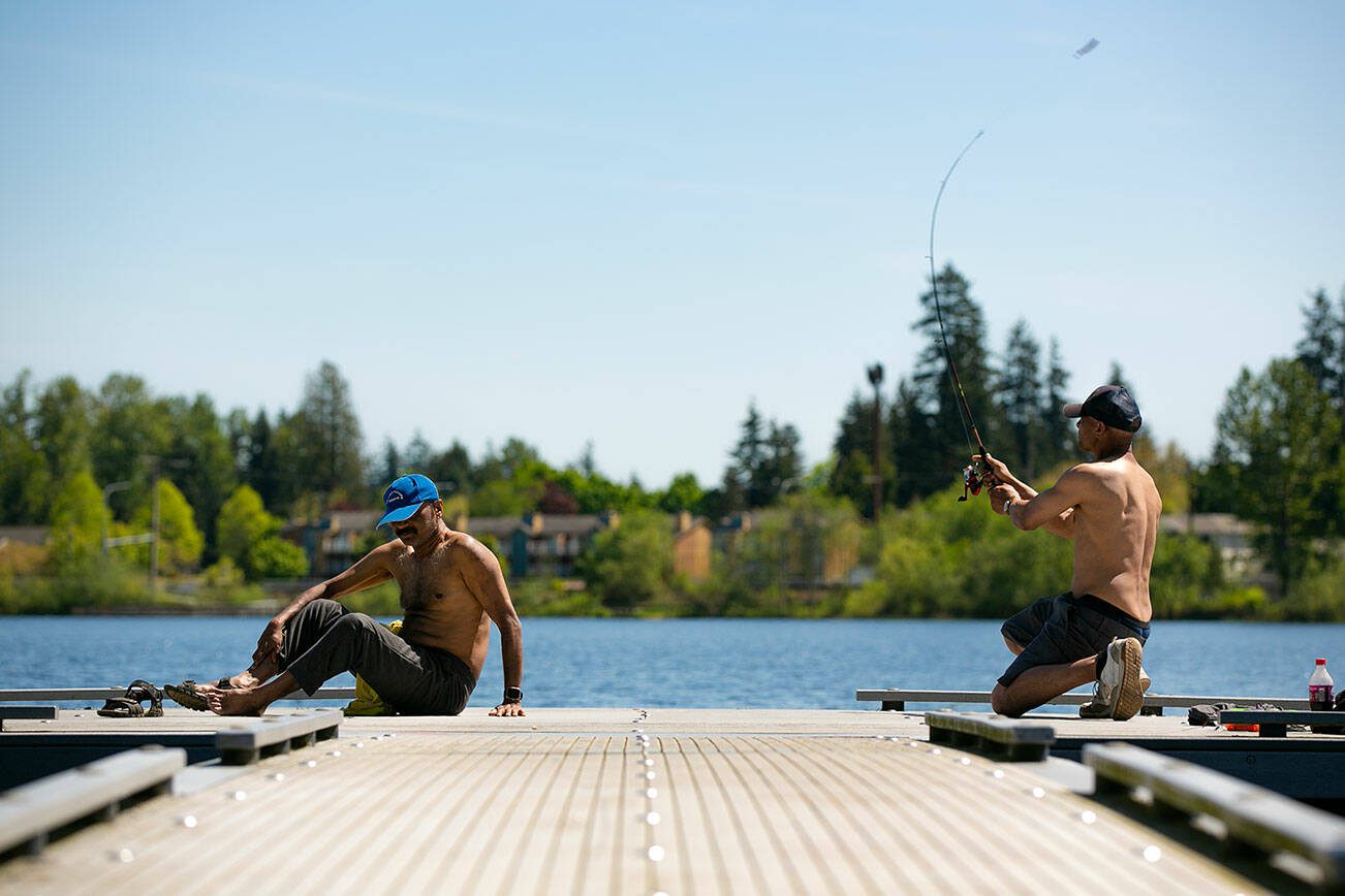 Two men bask in the sun while failing to get any fish to bite on a hot morning at Silver Lake on Friday, May 12, 2023, in Everett, Washington. The two said they typically have luck catching bass on plastic worms. (Ryan Berry / The Herald)