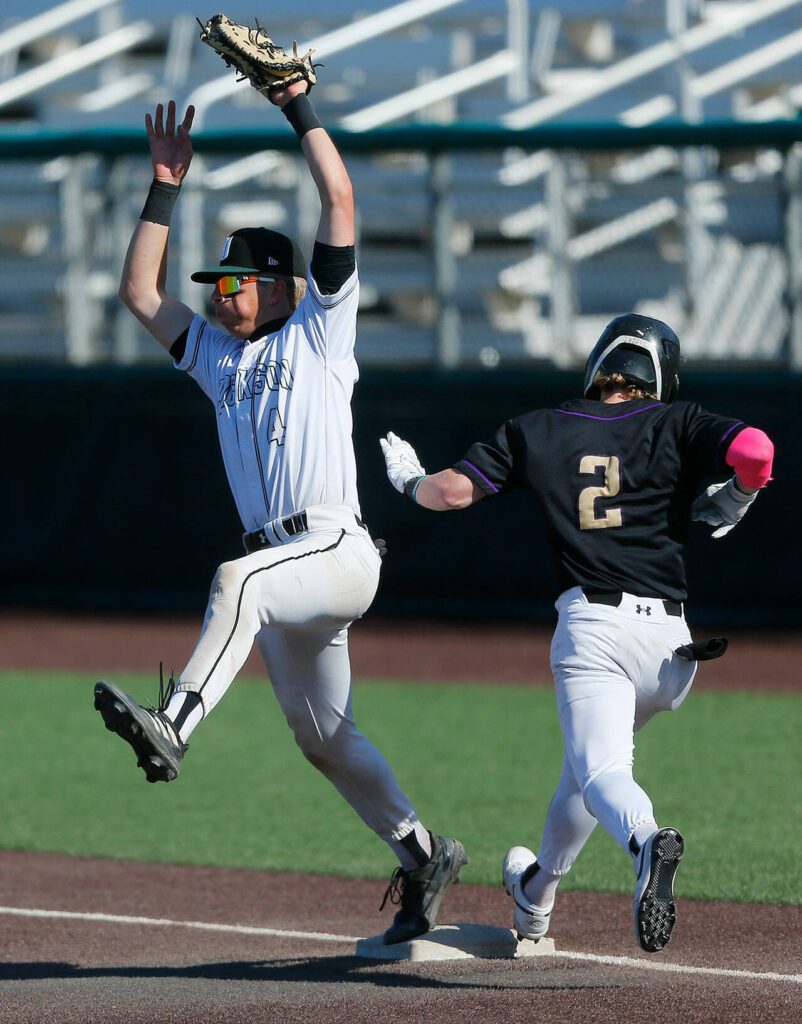 Jackson’s Caden Davis keeps his foot on first while snagging a high throw against Lake Stevens during a Wesco 4A District 1/2 game on Thursday, May 11, 2023, at Funko Field in Everett, Washington. The runner, Lake Stevens’ Aspen Alexander, was called safe. (Ryan Berry / The Herald)
