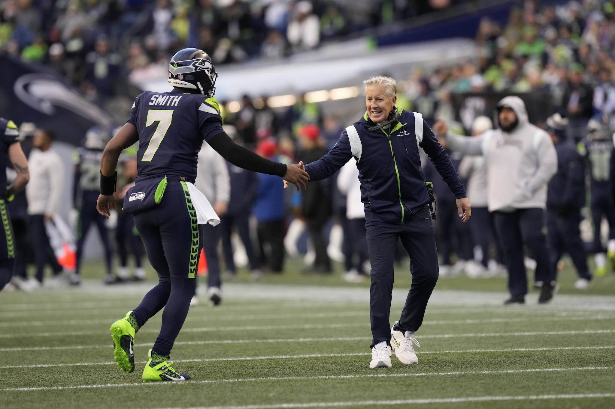 Seahawks quarterback Geno Smith (7) and head coach Pete Carroll shake hands during a game against the Raiders on Nov. 27, 2022, in Seattle. (AP Photo/Ben VanHouten)