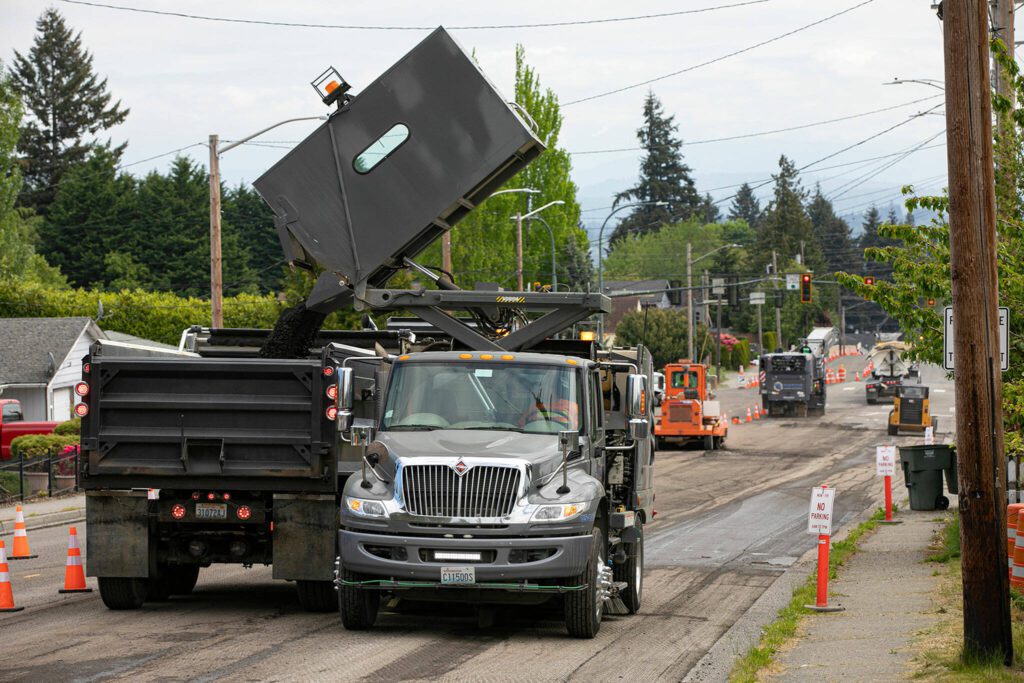 A street sweeper from Reece Construction Company dumps asphalt into a dump truck as milling gets underway on Madison Avenue on Tuesday, May 16, 2023, in Everett, Washington. (Ryan Berry / The Herald)
