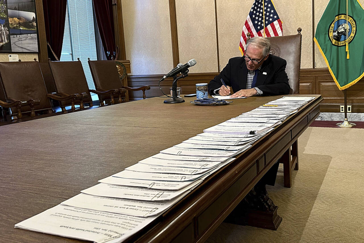 Gov. Jay Inslee signs bills at the Washington State Capitol, May 9, in Olympia. One of those bills was Senate Bill 5599, which was designed to protect homeless youths seeking reproductive health services or gender-affirming care. (Ed Komenda / Associated Press)