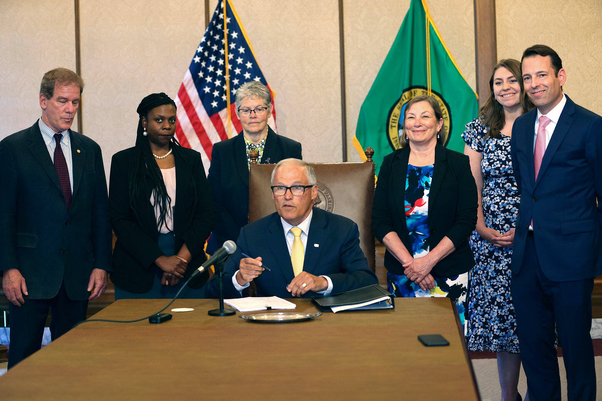 Gov. Jay Inslee signs Senate Bill 5536 concerning controlled substances on Tuesday, May 16, 2023, in Olympia, Wash. Behind him are from left to right: Rep. Roger Goodman, D- Kirkland, Rep. Jamila Taylor, D-Federal Way, House Speaker Laurie Jinkins, D-Tacoma, June Robinson, D-Everett, an identified woman and Andy Billig, D-Spokane. The policy, approved by Washinton lawmakers and signed by Inslee, keeps controlled substances illegal while boosting resources to help those struggling with addiction. (Karen Ducey/The Seattle Times via AP)