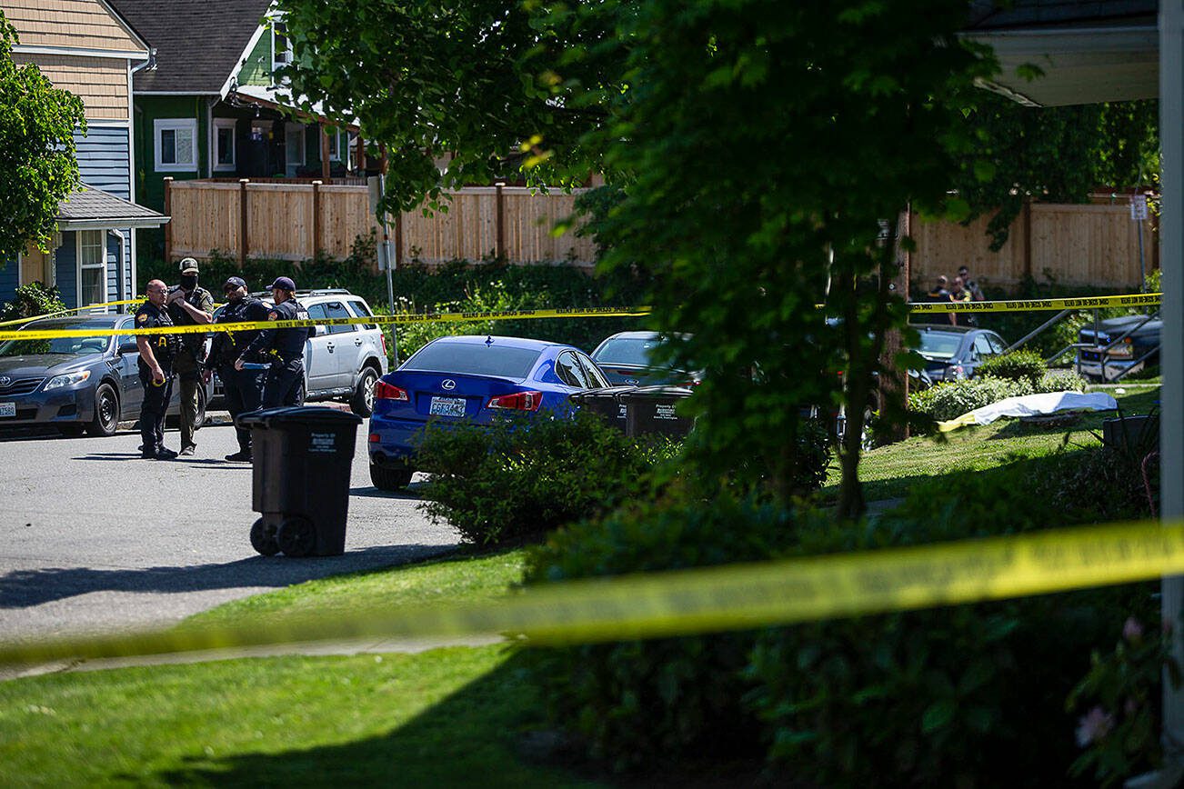 Police officers stand along Linden Street across from a body in the crime scene of a police involved shooting on Friday, May 19, 2023 in Everett, Washington. (Olivia Vanni / The Herald)