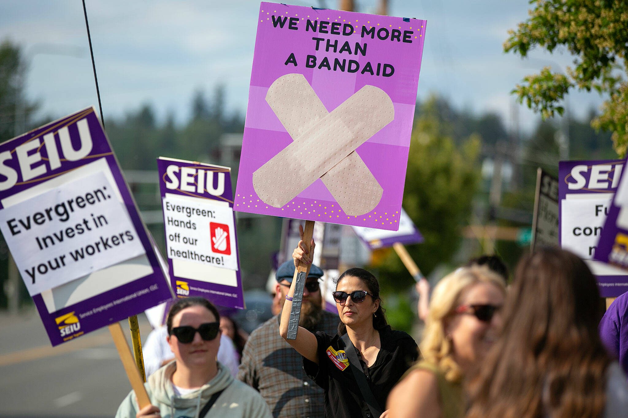 Emergency Room Technician Renee Uribe joins the picket line with a custom poster during a union protest in front of EvergreenHealth Monroe on Wednesday, May 24, 2023, in Monroe, Washington. (Ryan Berry / The Herald)
