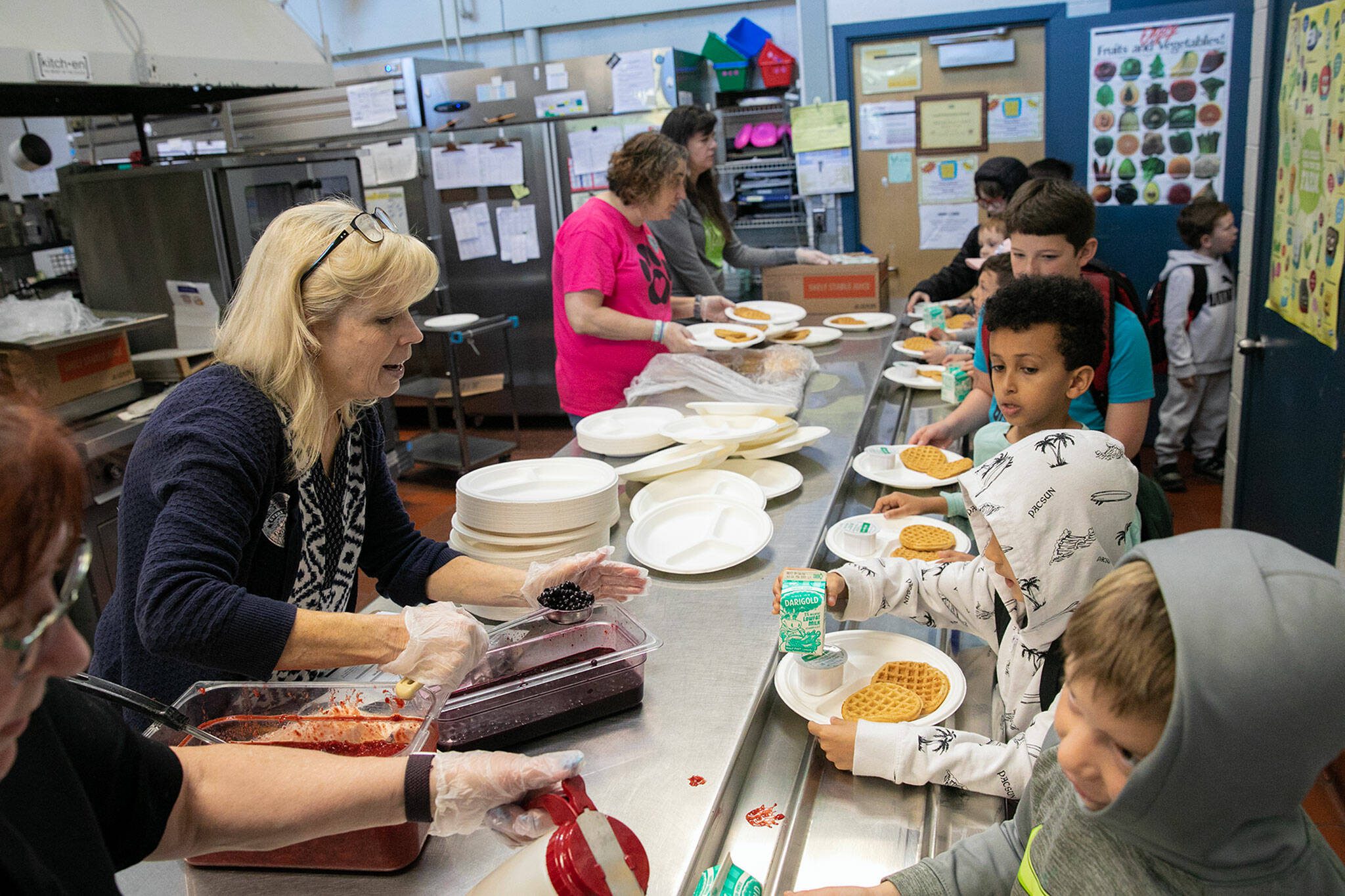 Students arriving off the bus get in line to score some waffles during a free pancake and waffle breakfast at Lowell Elementary School on Friday, May 26, 2023, in Everett, Washington. (Ryan Berry / The Herald)