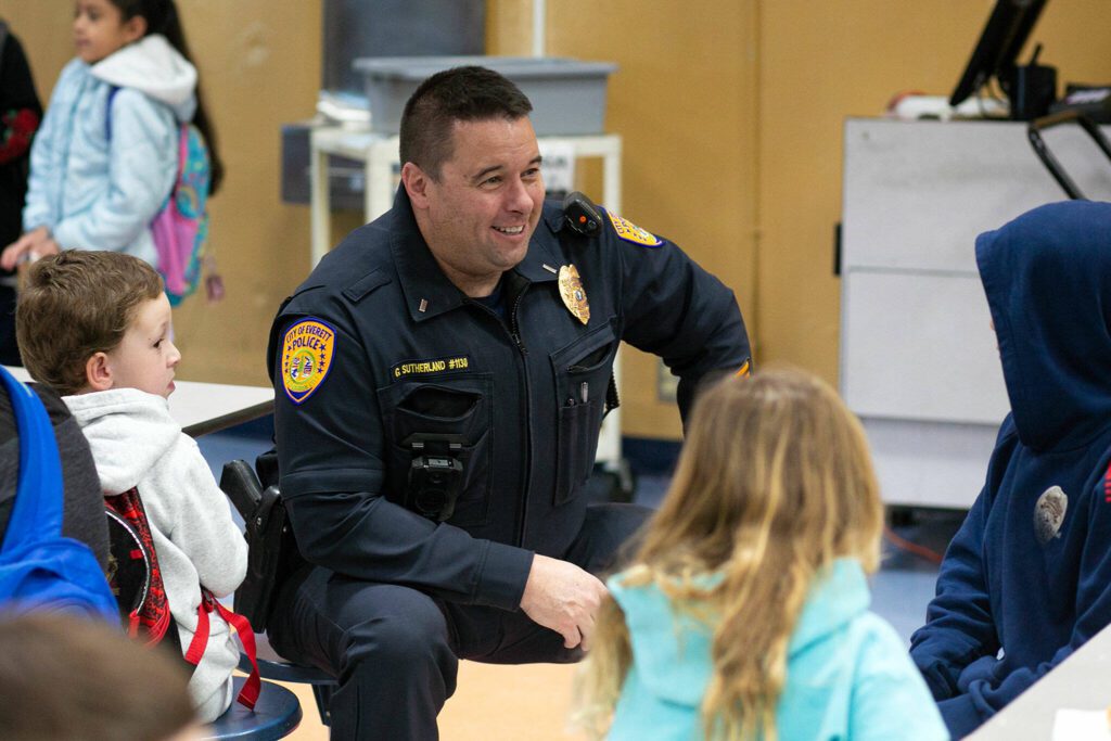 Lieutenant Greg Sutherland of the Everett Police Department hangs out with some students during a free pancake breakfast at Lowell Elementary School on Friday, May 26, 2023, in Everett, Washington. (Ryan Berry / The Herald)
