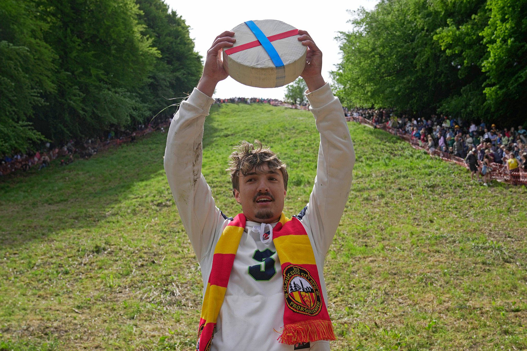 Cooper Cummings celebrates after winning a men’s downhill during the Cheese Rolling contest at Cooper’s Hill in Brockworth, Gloucestershire, Monday May 29, 2023. The Cooper’s Hill Cheese-Rolling and Wake is an annual event where participants race down the 200-yard (180 m) long hill chasing a wheel of double gloucester cheese. (AP Photo/Kin Cheung)