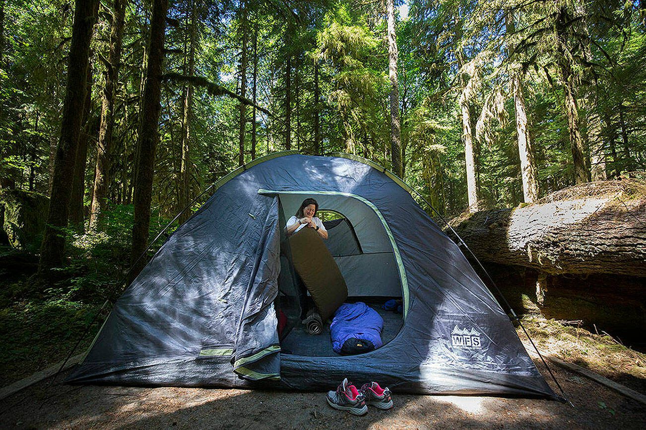 Tracey Silla of Everett leaves her shoes outside as she sets up sleeping bags and pads in her tent at Gold Basin Campground. (Andy Bronson / The Herald)