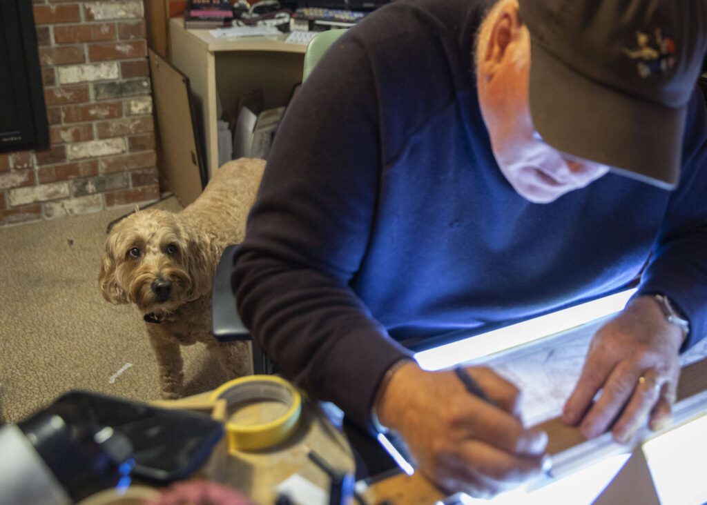 Brian Basset’s dog Astro looks up at him while Basset works in his studio on Wednesday, June 7, 2023, in Edmonds, Washington. (Olivia Vanni / The Herald)
