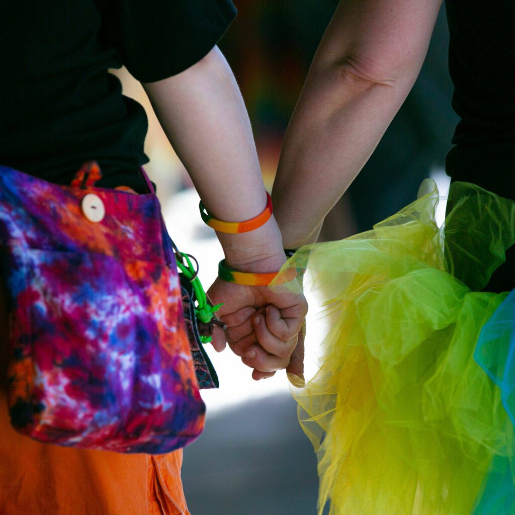 Two people hold hands as they walk around taking in the sights during Snohomish’s inaugural Pride celebration on Saturday, June 3, 2023, in downtown Snohomish, Washington. (Ryan Berry / The Herald)
