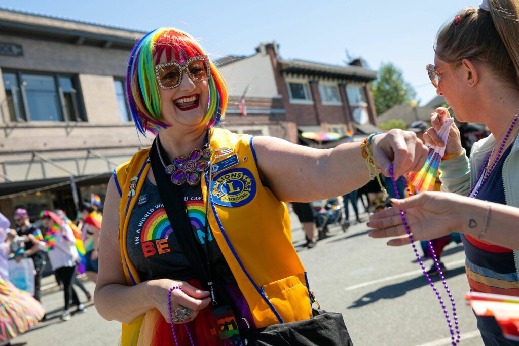A person hands out beads as they parade down First Street during Snohomish’s inaugural Pride celebration on Saturday, June 3, 2023, in downtown Snohomish, Washington. (Ryan Berry / The Herald)
