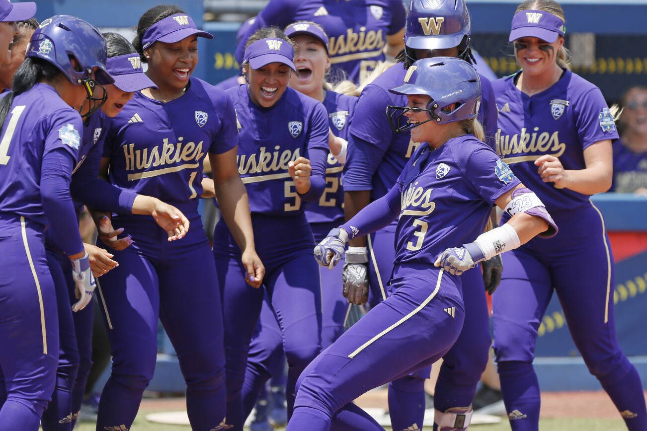 Washington celebrates a home run by Rylee Holtorf (3) at home plate during the second inning of an NCAA softball Women's College World Series game against Utah Friday, June 2, 2023, in Oklahoma City. (AP Photo/Nate Billings)