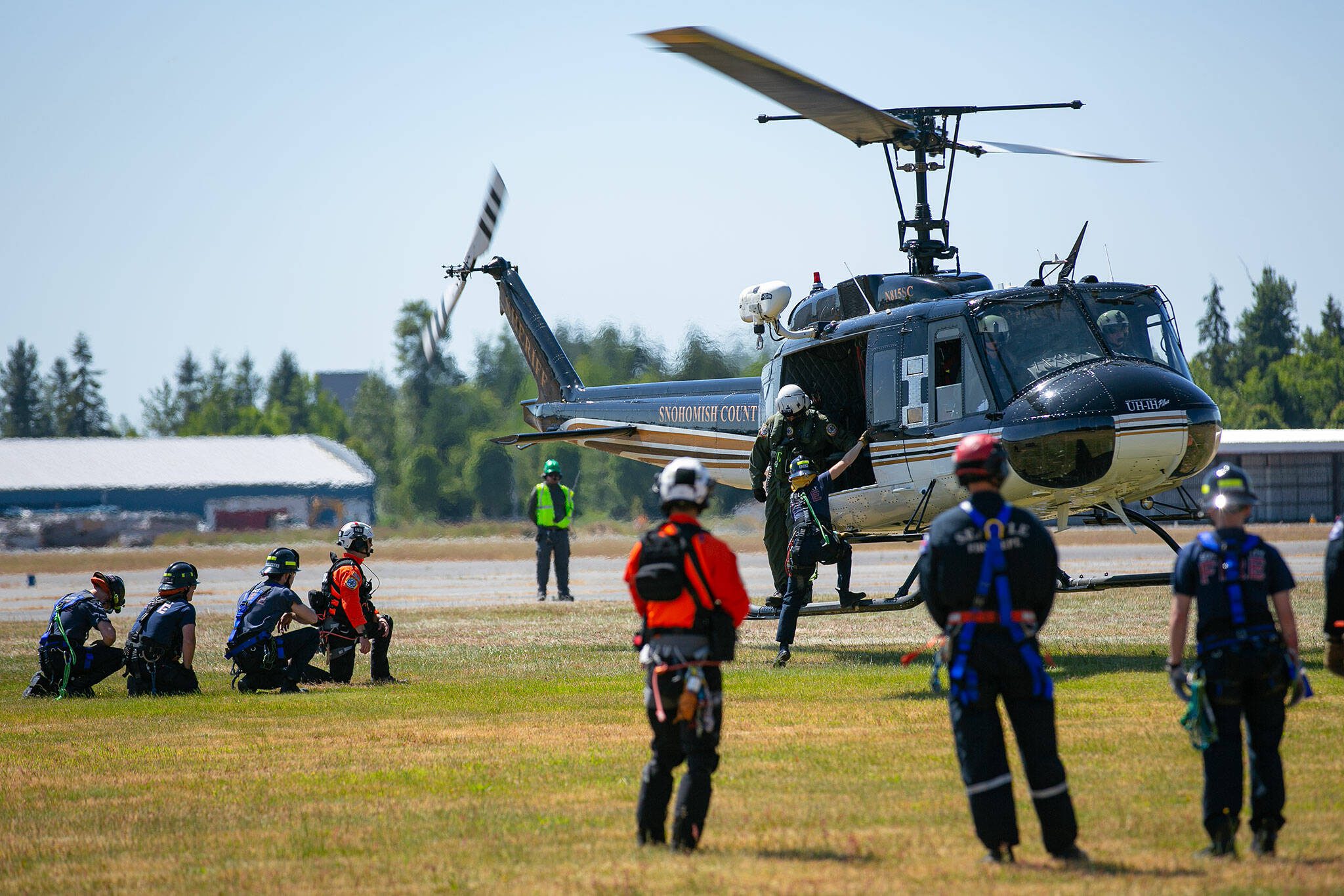 Members of South County Fire practice onboarding and offboarding a hovering Huey helicopter during an interagency disaster response training exercise at Arlington Municipal Airport on Tuesday, June 6, 2023, in Arlington, Washington. The crews learned about and practiced safe entry and exit protocols with crew from Snohomish County Volunteer Search and Rescue before being given a chance to do a live training. (Ryan Berry / The Herald)