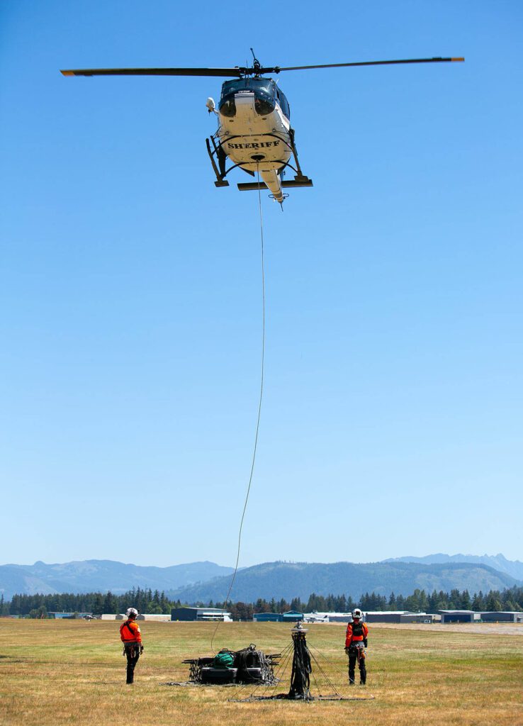 Snohomish County Volunteer Search and Rescue’s flight crew demonstrate attaching and lifting gear with a sling load during an interagency disaster response training exercise at Arlington Municipal Airport on Tuesday, June 6, 2023, in Arlington, Washington. (Ryan Berry / The Herald)
