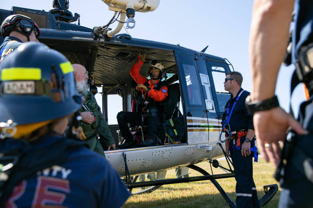 Helicopter Rescue Technician Andy Toyota shows emergency workers how to strap into a helicopter during an interagency disaster response training exercise at Arlington Municipal Airport on Tuesday, June 6, 2023, in Arlington, Washington. (Ryan Berry / The Herald)
