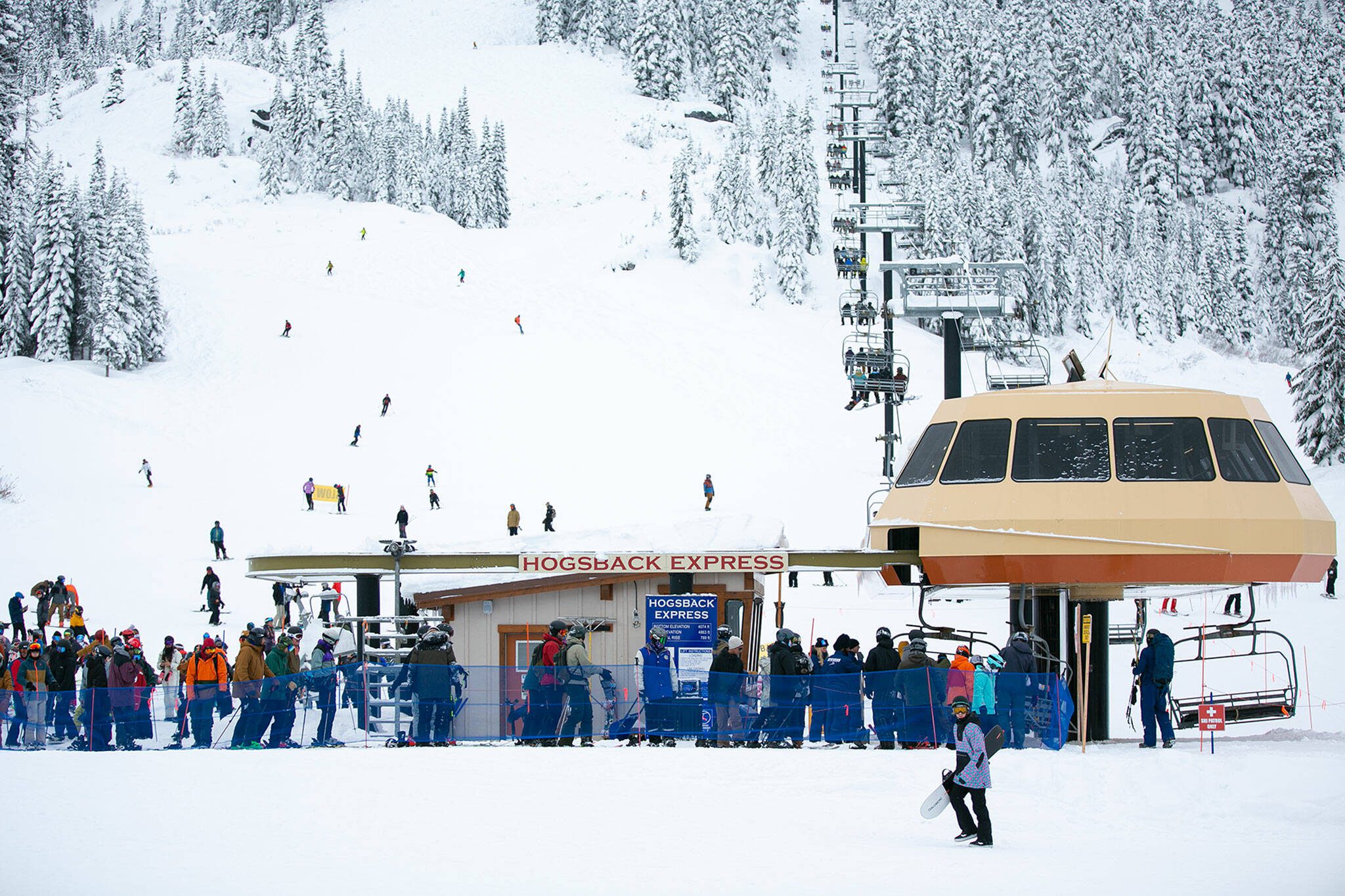 The line for a lift grows steadily as more people arrive throughout the day on the opening day of ski season at Stevens Pass Ski Area on Friday, Dec. 2, 2022, near Skykomish, Washington. (Ryan Berry / The Herald)