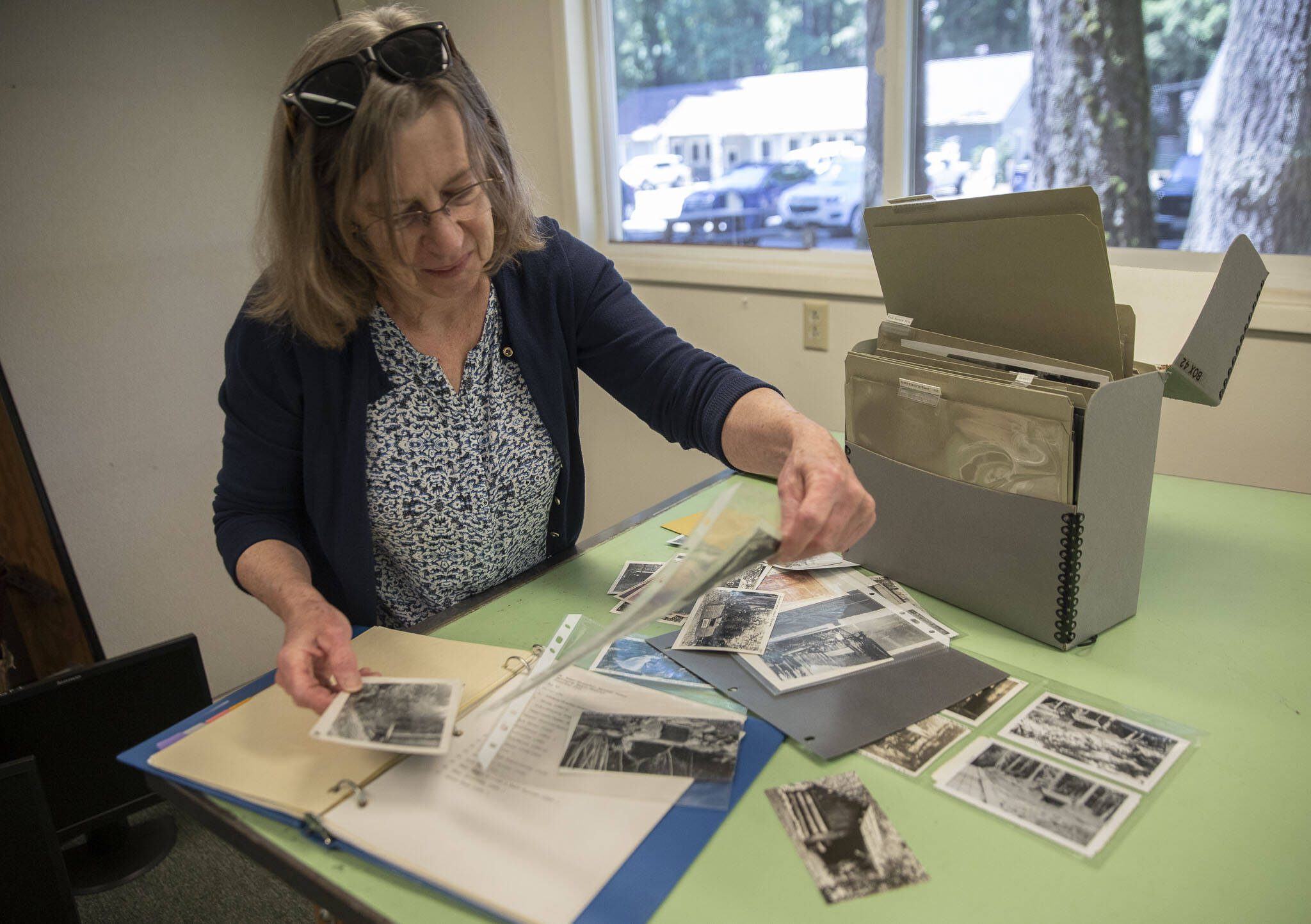 Erika Morris, an information specialist at the Darrington Ranger district and a member of the Darrington Historical Society, sorts through photographs being archived at the Darrington Ranger Station on Tuesday, June 6, 2023 in Darrington, Washington. (Olivia Vanni / The Herald)