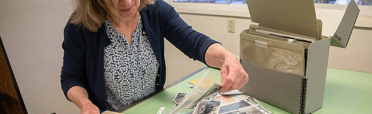 Erika Morris, an information specialist at the Darrington Ranger district and a member of the Darrington Historical Society, sorts through photographs being archived at the Darrington Ranger Station on Tuesday, June 6, 2023 in Darrington, Washington. (Olivia Vanni / The Herald)