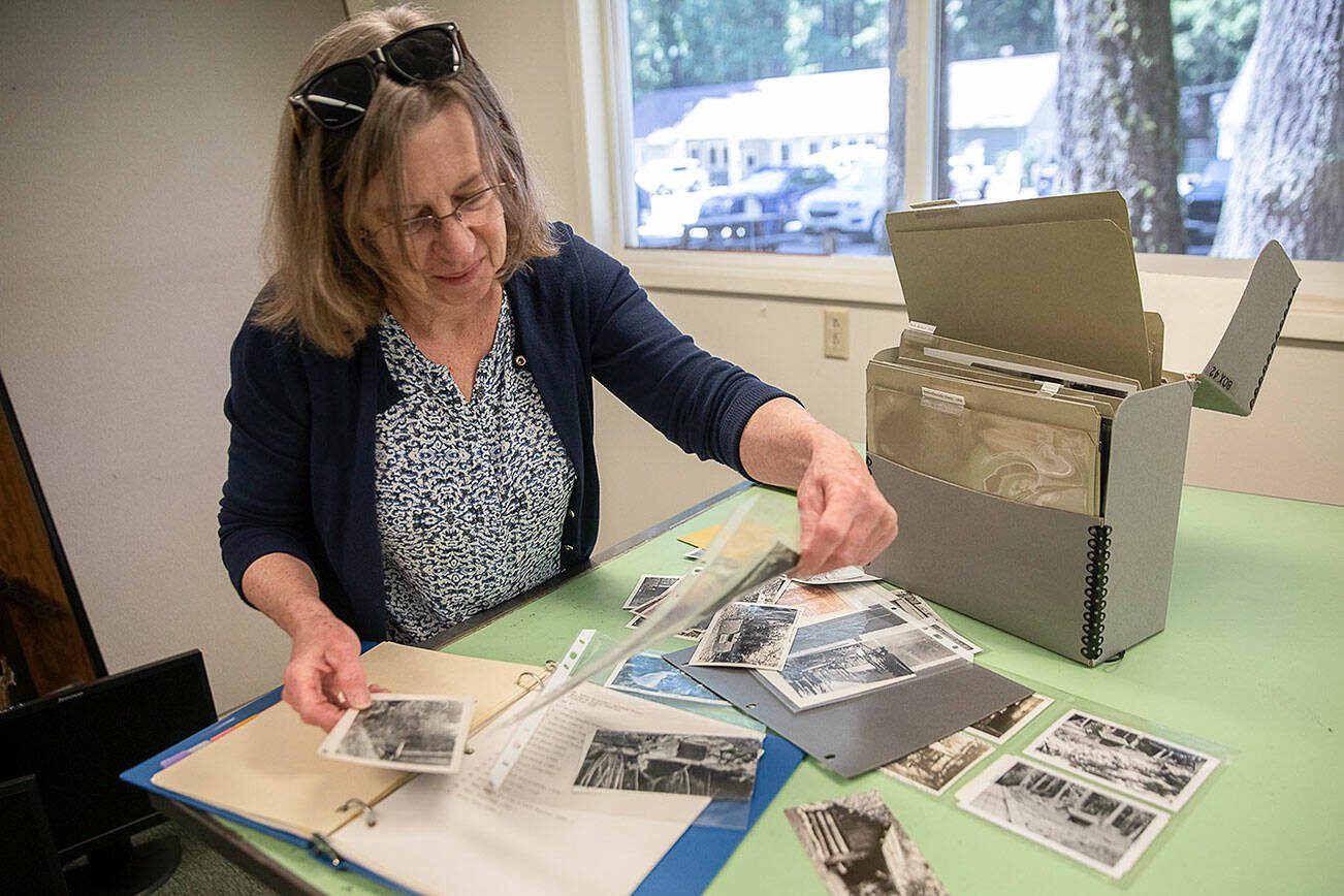 Erika Morris, an information specialist at the Darrington Ranger district and a member of the Darrington Historical Society, sorts through photographs being archived at the Darrington Ranger Station on Tuesday, June 6, 2023 in Darrington, Washington. (Olivia Vanni / The Herald)