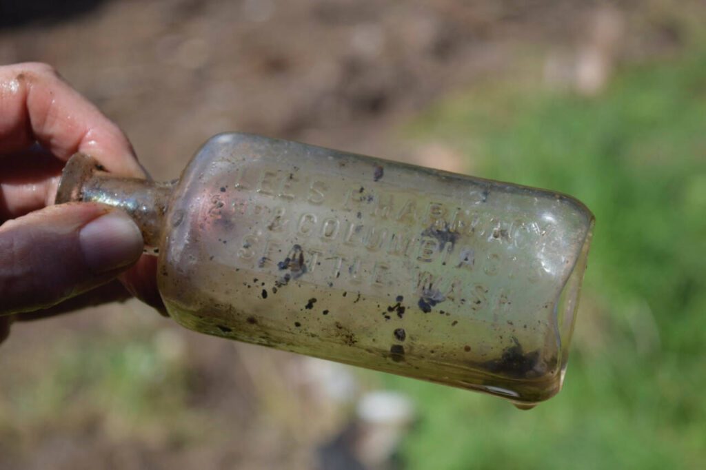 This old medicine bottle from Lee’s Pharmacy in Seattle was found in the dirt outside the log cabin. (Photo by Patricia Guthrie)
