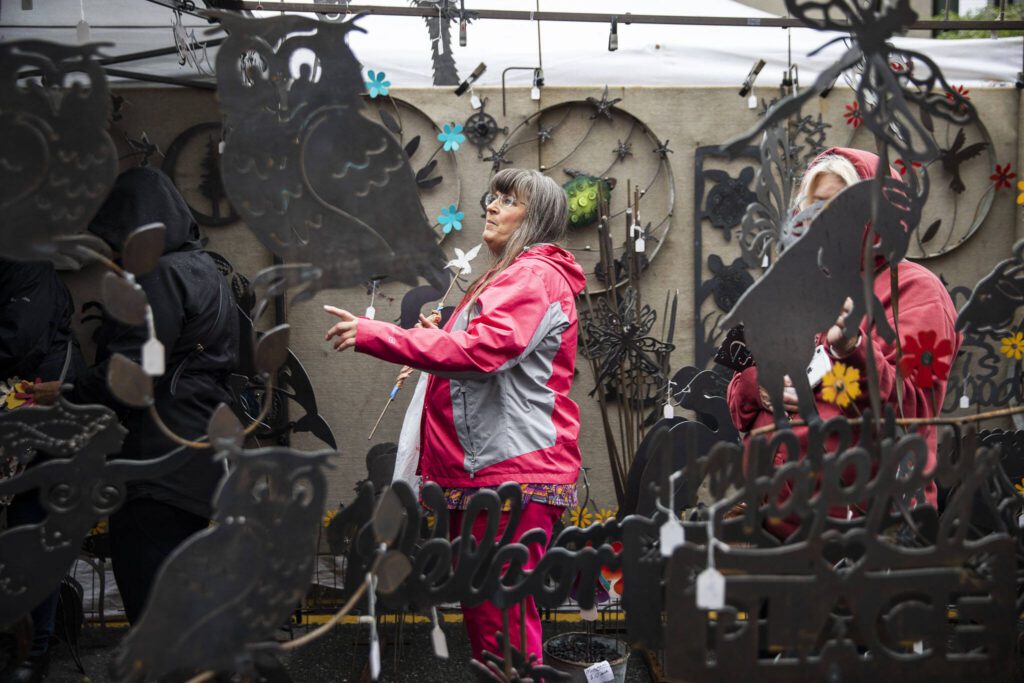 Tammy Brockmann looks though the different metal cutouts available at the Freeborn Metal Art booth during the first day of Sorticulture on Friday, June 9, 2023 in Everett, Washington. (Olivia Vanni / The Herald)
