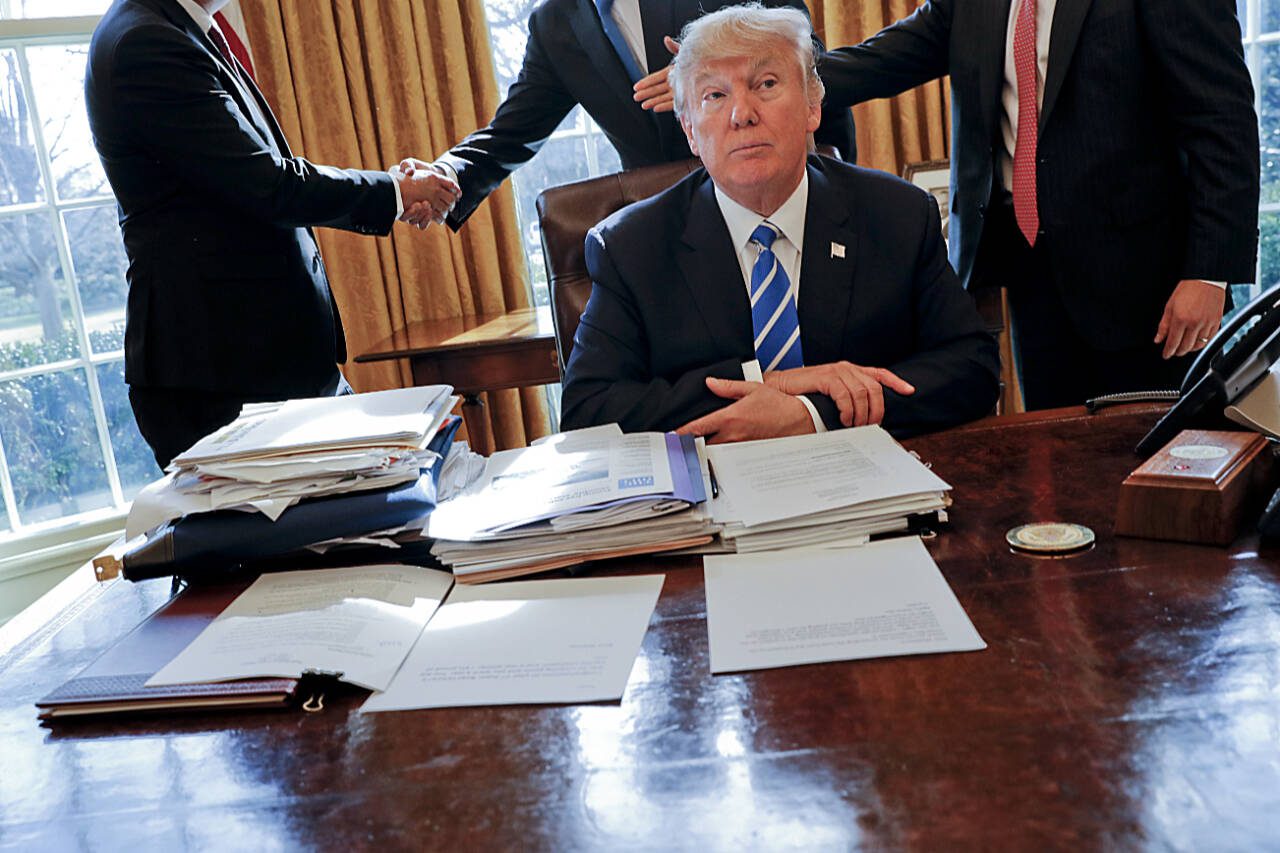 Then President Donald Trump sits at his desk after a meeting with Intel CEO Brian Krzanich( left) and members of his staff in the Oval Office of the White House in Washington, Feb. 8, 2017, as a document lockbag is visible on the desk, the key still inside at left. (Pablo Martinez Monsivais / Associated Press file photo)