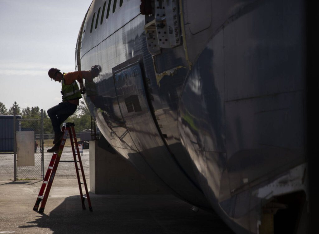 A man climbs out of the fuselage after it is placed on Thursday, June 15, 2023 in Everett, Washington. (Olivia Vanni / The Herald)
