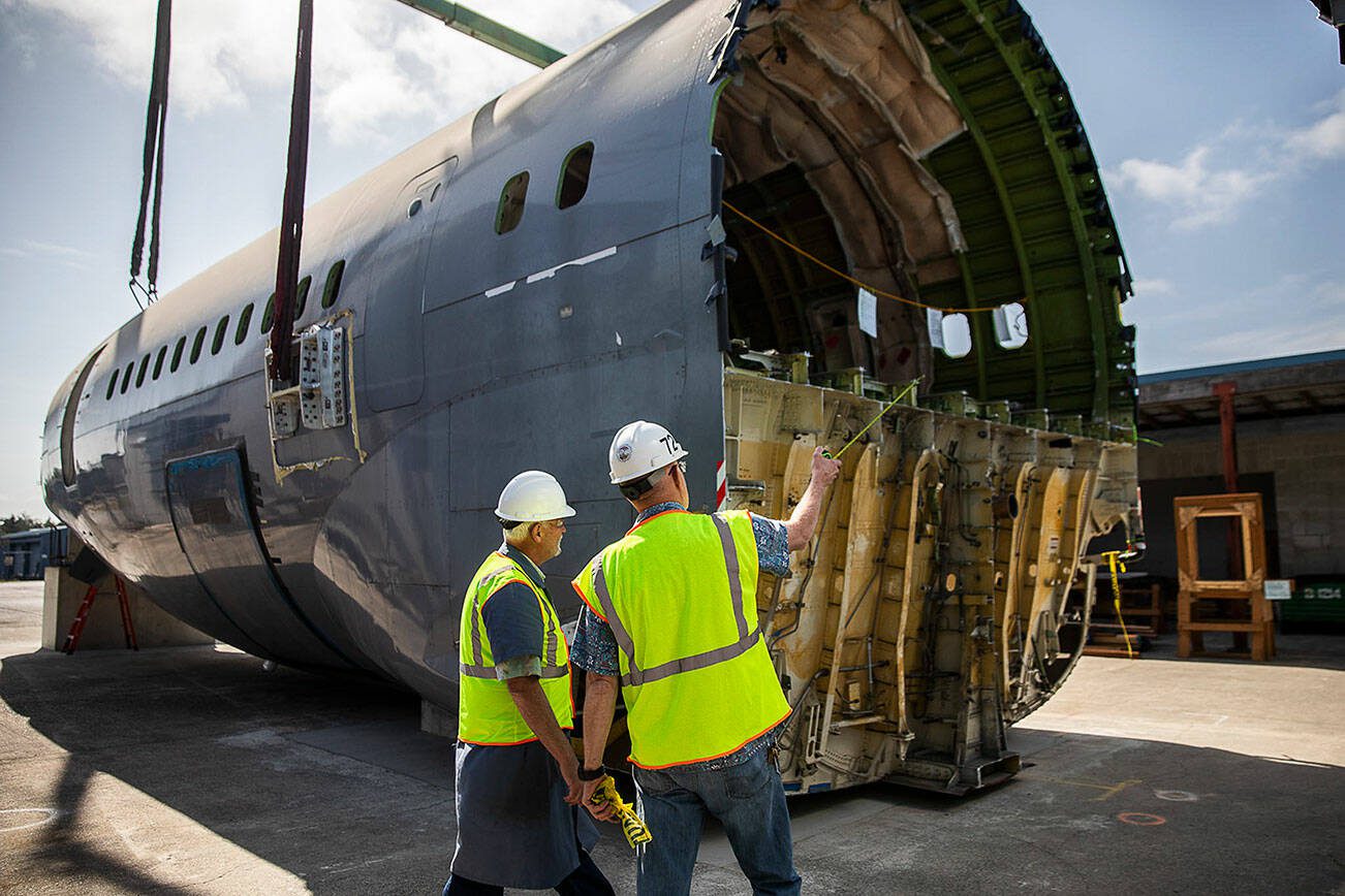 Brian Wilson, left, and Ron Fronheiser, right, survey the fuselage after it is placed at Edmonds College’s Advance Manufacturing Skill Center at Paine Field on Thursday, June 15, 2023 in Everett, Washington. (Olivia Vanni / The Herald)
