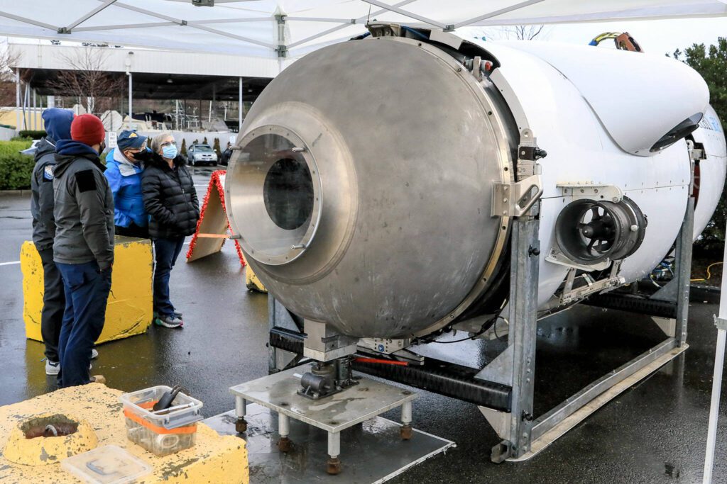 Ryan Stalkfleet, left to right, and Kenny Hauge, members of the OceanGate submersible crew, explains the vehicles features and operations to Bill McFerren and Kiely McFerren at the Port of Everett on December 16, 2021. (Kevin Clark / Herald file)

