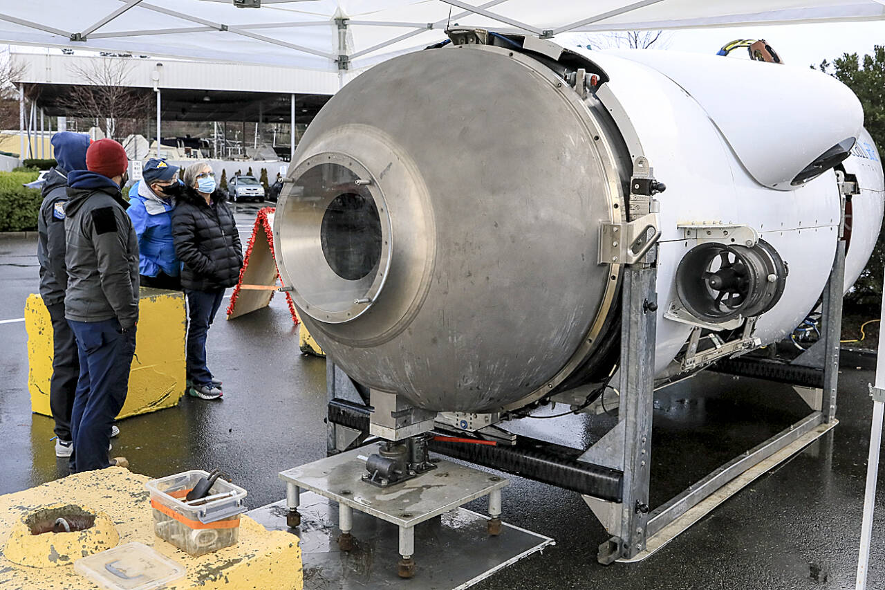 Ryan Stalkfleet (left) and Kenny Hauge, employees of Everett-based OceanGate, explain the features and operations of an OceanGate submersible to Bill McFerren and Kiely McFerren at the Port of Everett in December, 2021. (Kevin Clark / The Herald)