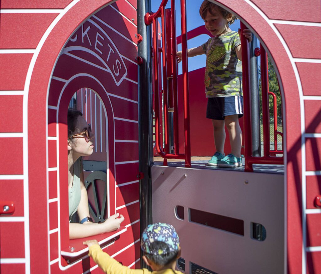 Left to right, Abby Sham, 31, Rowan Sham, 2, and Taka Swaback, 3, play on a structure at the Hazel Miller Universally Accessible Playground at Ballinger Park in Mountlake Terrace, Washington on Wednesday, June 28, 2023. (Annie Barker / The Herald)
