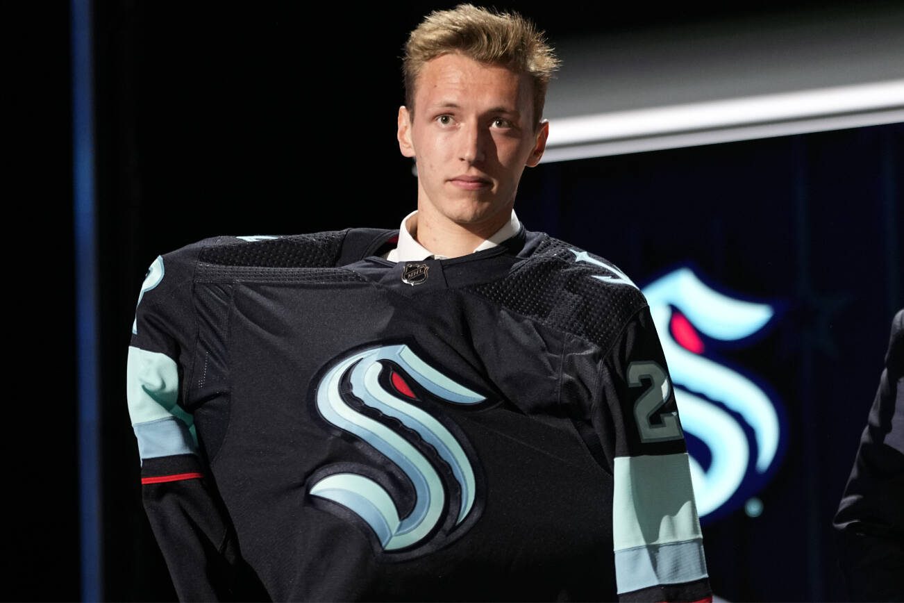 Eduard Sale puts on a Seattle Kraken jersey after being picked by the team during the first round of the NHL hockey draft Wednesday, June 28, 2023, in Nashville, Tenn. (AP Photo/George Walker IV)