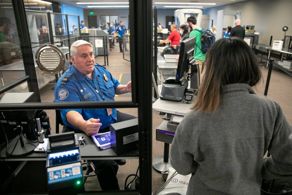 Transportation Security Officer Jerry Drews speaks with a traveler in the TSA security line Friday, May 27, 2022, at Paine Field in Everett, Washington. (Ryan Berry / The Herald)
